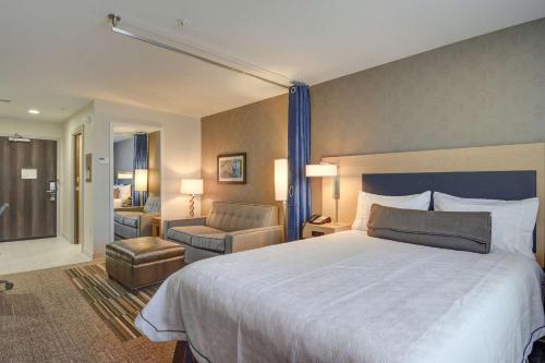 Home2 Suites by Hilton Irving/DFW Airport North في ايرفينغ: غرفة فندقية بسرير كبير وكرسي