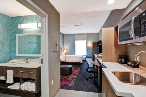 a bathroom with a sink and a room with a bed at Home2 Suites By Hilton McKinney in McKinney