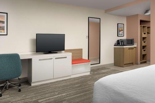 a hotel room with a bed and a television on a desk at Hilton Garden Inn Dallas/Duncanville in Duncanville