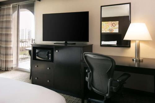 a hotel room with a desk with a television and a chair at DoubleTree by Hilton Dallas Market Center in Dallas