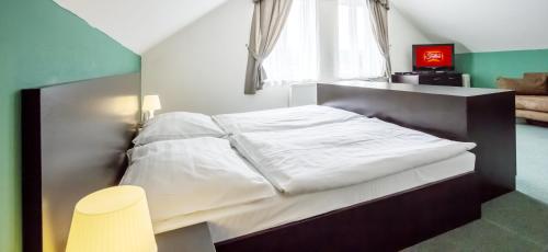 a small bedroom with a bed with white sheets at Garni HOTEL Fellini in Žiar nad Hronom