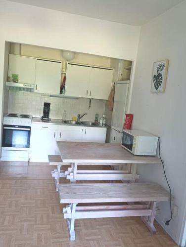 a kitchen with white cabinets and a table with a microwave at Rauhallinen kaksio, puusauna käytettävissä in Varkaus