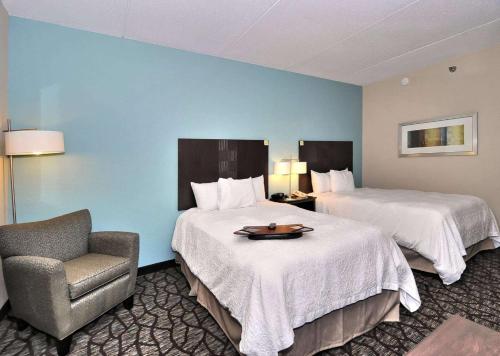 a hotel room with two beds and a chair at Hampton Inn Eden in Eden
