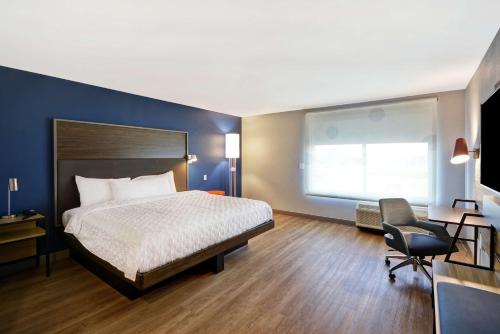 a bedroom with a bed and a desk and a chair at Tru By Hilton Beavercreek Dayton in Fairborn