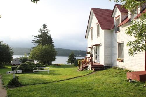 a white house with a view of the water at Mountain Vista Seaside Cottages in Big Bras d'Or