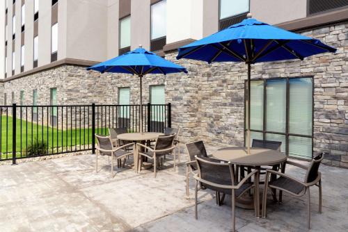 a patio with tables and chairs with blue umbrellas at Hampton Inn & Suites Xenia Dayton in Xenia
