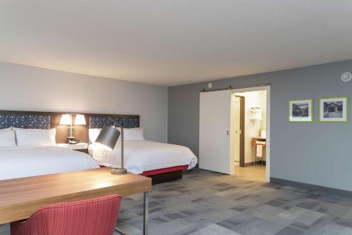 a hotel room with two beds and a desk and a table at Hampton Inn & Suites Xenia Dayton in Xenia