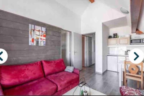 un salon avec un canapé rouge et une cuisine dans l'établissement Penthouse T2 Valmeinier 1900 skis aux pieds, à Valmeinier