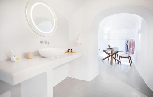Baño blanco con lavabo y espejo en Rafael' s Mediteranian Cave Suites en Firostefani