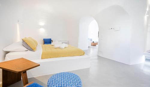 a white bedroom with a bed and a table at Rafael' s Mediteranian Cave Suites in Firostefani