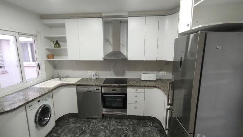 a kitchen with white cabinets and a stainless steel refrigerator at Piso de 110 m2 en el centro de Figueres in Figueres