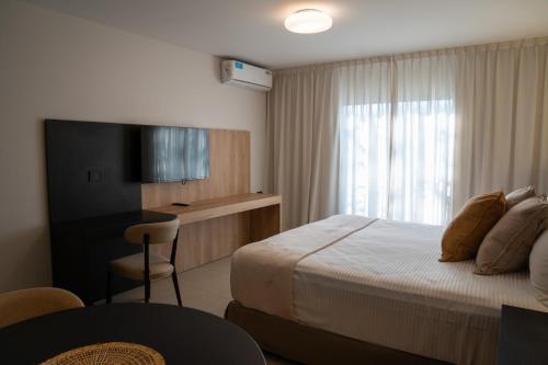 a hotel room with a bed and a desk and a television at Urbana Suites in Mendoza