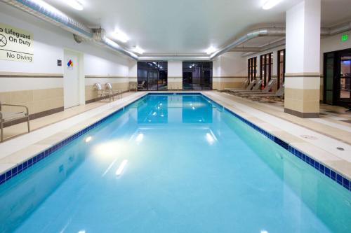 a large swimming pool with blue water in a building at Hampton Inn & Suites Denver Airport / Gateway Park in Aurora
