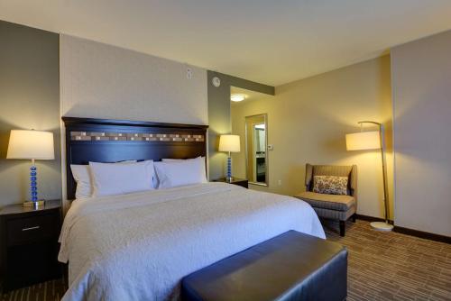 a hotel room with a large bed and a chair at Hampton Inn & Suites Denver Airport / Gateway Park in Aurora