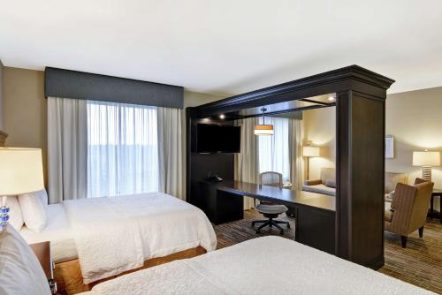 a hotel room with two beds and a desk at Hampton Inn & Suites Denver Airport / Gateway Park in Aurora