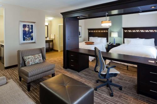 een hotelkamer met een slaapkamer met een bureau en een bed bij Hampton Inn & Suites Denver Airport / Gateway Park in Aurora