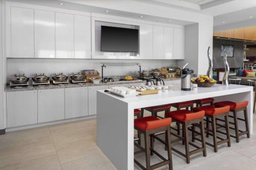 eine Küche mit weißen Schränken und roten Barhockern in der Unterkunft Hilton Garden Inn Denver/Thornton in Thornton