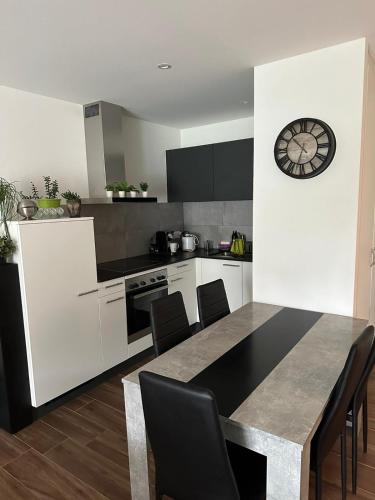 a kitchen with a table and a clock on the wall at Luxu’rooms in Lignières