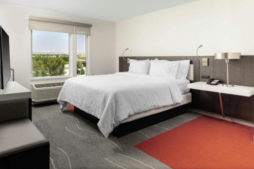 a bedroom with a large bed and a large window at Hilton Garden Inn Denver/Thornton in Thornton