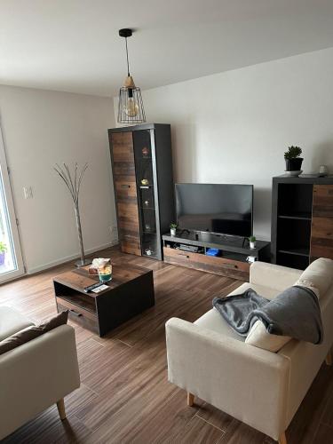 een woonkamer met een bank en een flatscreen-tv bij Luxu’rooms in Lignières