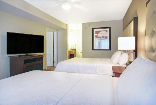 a hotel room with two beds and a flat screen tv at Homewood Suites by Hilton Denver International Airport in Aurora