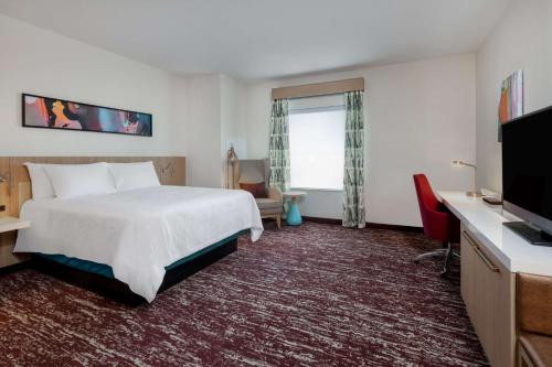 a hotel room with a bed and a flat screen tv at Hilton Garden Inn Longmont in Longmont