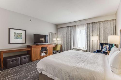 a hotel room with a bed and a flat screen tv at Hampton Inn & Suites Dallas/Ft. Worth Airport South in Euless