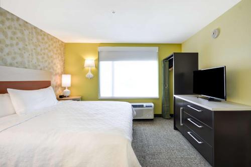 a hotel room with a bed and a flat screen tv at Home2 Suites By Hilton Dallas North Park in Dallas