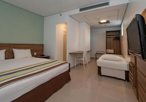 a hotel room with a bed and a flat screen tv at Express Vieiralves in Manaus