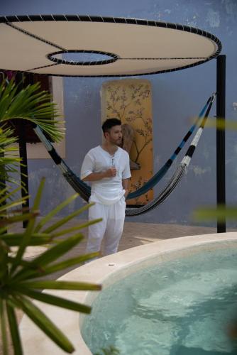 a man standing in a hammock next to a swimming pool at Las Lupitas Hotel Boutique in Campeche