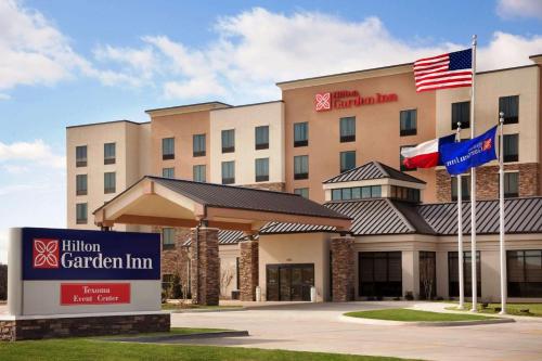 a hotel with flags in front of a building at Hilton Garden Inn Denison/Sherman/At Texoma Event Center in Sherman