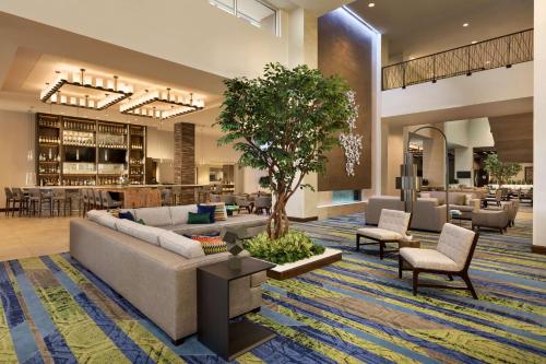 a lobby with a couch and a tree in the middle at Embassy Suites By Hilton Denton Convention Center in Denton