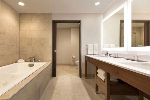 a bathroom with two sinks and a bath tub and a tubermott at Embassy Suites By Hilton Denton Convention Center in Denton