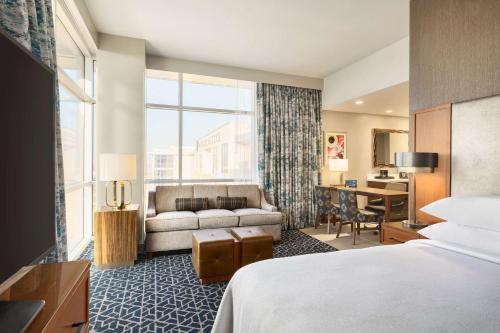Habitación de hotel con cama, sofá y escritorio en Embassy Suites By Hilton Denton Convention Center, en Denton