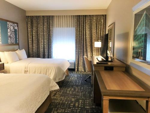 a hotel room with two beds and a desk and a television at Hampton Inn & Suites Dallas-The Colony in The Colony
