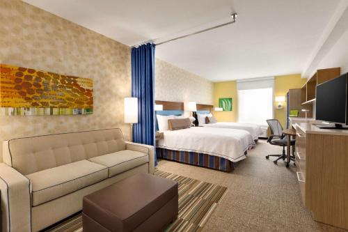 Home2 Suites by Hilton Destin في ديستين: غرفه فندقيه بسرير واريكه