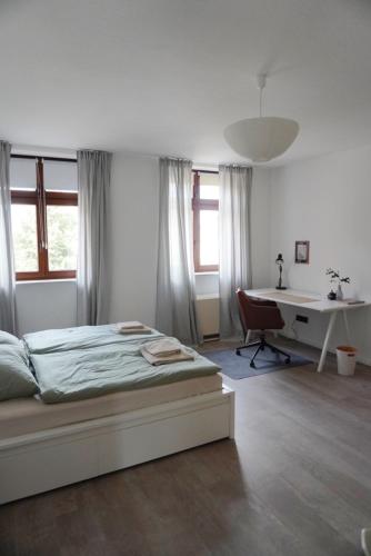 a white bedroom with a bed and a desk at Wohnen im alten Standesamt in Pasewalk