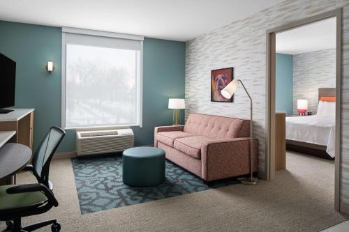 a hotel room with a pink couch and a bed at Home2 Suites by Hilton Des Moines at Drake University in Des Moines