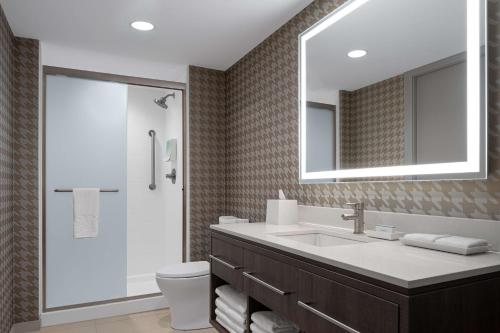 a bathroom with a sink and a toilet and a mirror at Home2 Suites by Hilton Des Moines at Drake University in Des Moines