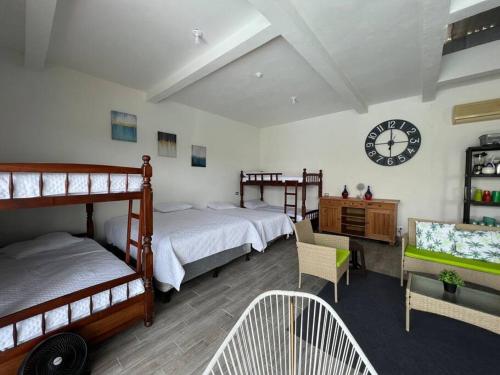 Taxisco的住宿－Las Villas Taxisco，一间卧室设有两张床,墙上挂着一个时钟。