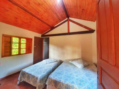 1 dormitorio con cama y techo de madera en Chalé e Camping Elementais en São Thomé das Letras