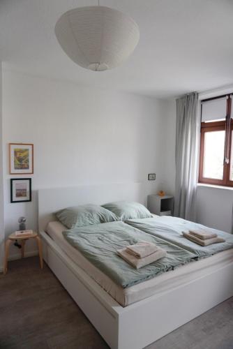 a white bedroom with a large bed with a large light fixture at Wohnen im alten Standesamt in Pasewalk