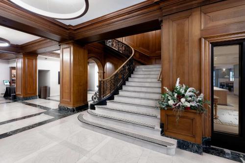 a lobby with a staircase with a flower arrangement at Hotel Fort Des Moines, Curio Collection By Hilton in Des Moines