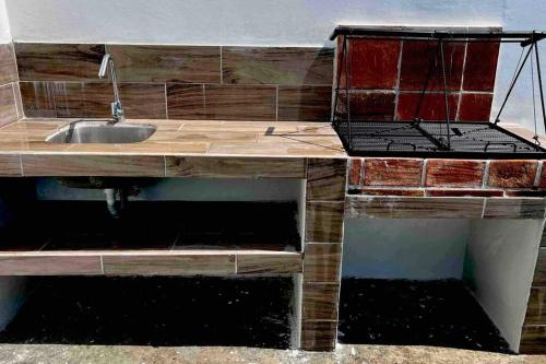 um balcão de cozinha com um lavatório e um grelhador em Las Villas Taxisco em Taxisco