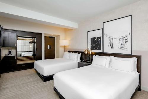 a hotel room with two beds and a bathroom at Hotel Fort Des Moines, Curio Collection By Hilton in Des Moines