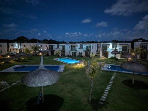 un patio del complejo con 2 piscinas y sombrillas por la noche en Blissful Abode GV, en Grand Gaube