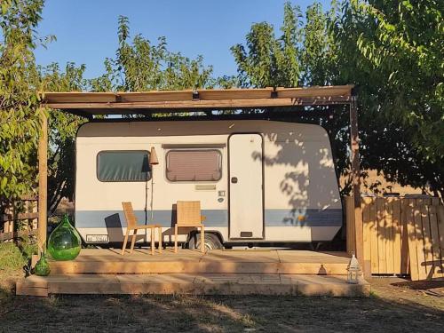 a caravan with a table and chairs under a shed at Home Shanti, relax tra i ciliegi in Crespellano