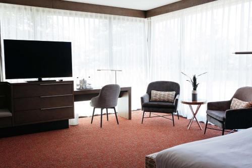 a hotel room with a television and a desk and chairs at Revel Hotel, Tapestry Collection By Hilton in Urbandale