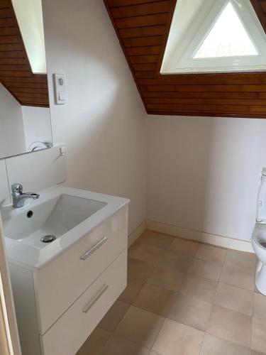 une salle de bain avec un lavabo blanc et une fenêtre dans l'établissement Chez Pierrot et Lucienne au bord de la mer, à Plouguerneau