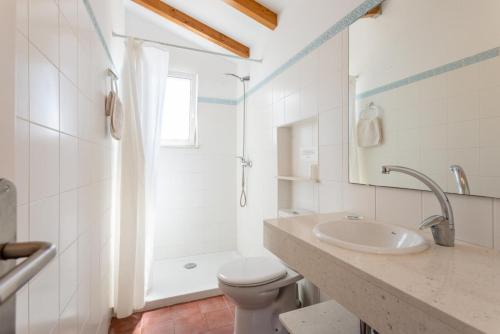 ein weißes Bad mit einem Waschbecken und einem WC in der Unterkunft Voramar Waterfront in Sant Lluís